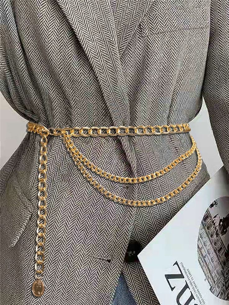 Layered gold chain belt worn over a herringbone jacket
