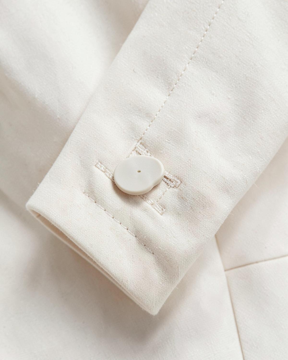 Matte resin button and topstitching on a cream blazer cuff